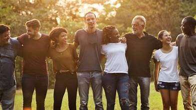 group of diverse people standing arm in arm outdoors
